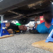 Greg and Ryan under the car appraising the damage. For some reason that I can not quite understand, Greg appears to be smiling.