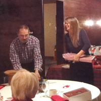 Meg Anderson about to tear the paper off her choice (while a photo of LAST year's buffet plays on Tom's laptop) ...