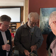 Something on Tom's tablet has the attention of Kevin and George